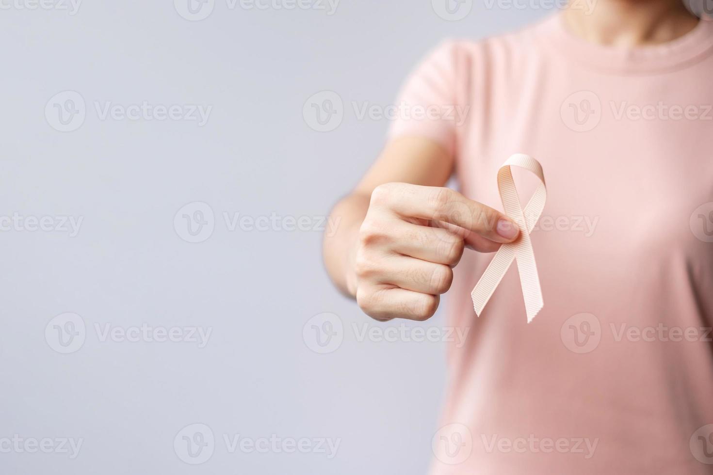vrouw hand met perzik lint voor september baarmoederkanker bewustzijn maand. gezondheidszorg en wereld kanker dag concept foto
