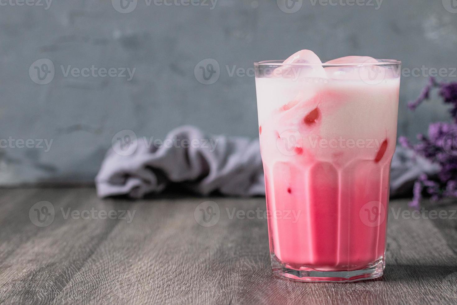 koude roze melk koud drankje in helder glas op grijze achtergrond. Thaise melk foto