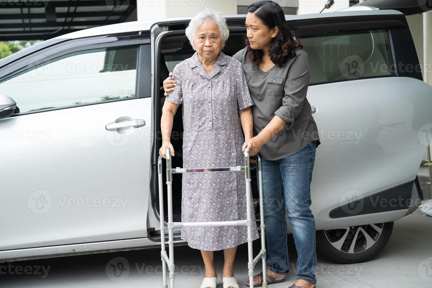 verzorger dochter helpt en ondersteunt aziatische senior of oudere oude dame vrouw patiënt bereidt zich voor om uit haar auto te stappen. foto