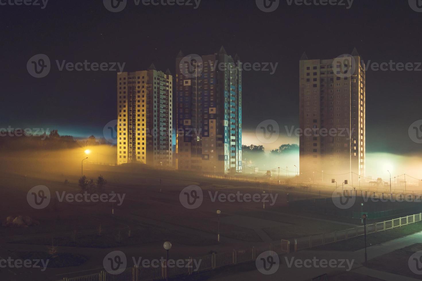 nachtpanorama van woonwijk met hoogbouw in de mist vroeg in de ochtend foto