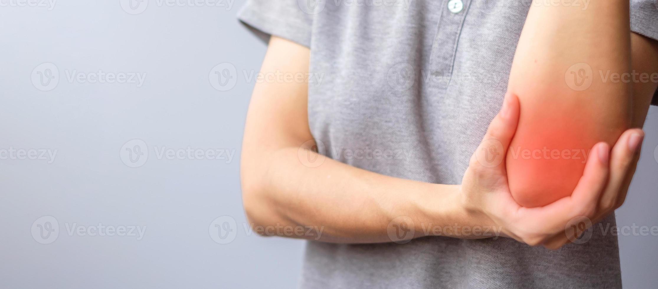 volwassen vrouw met haar spierpijn op grijze achtergrond. vrouw met elleboogpijn als gevolg van laterale epicondylitis of tenniselleboog. verwondingen en medisch concept foto