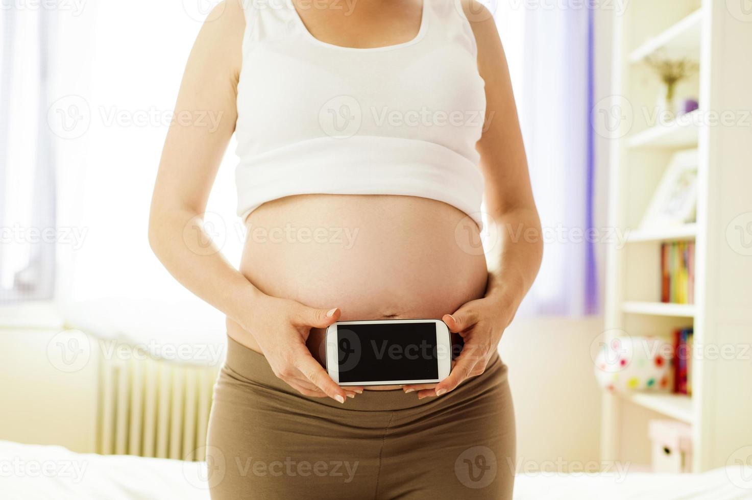 zwangere vrouw met mobiele telefoon foto