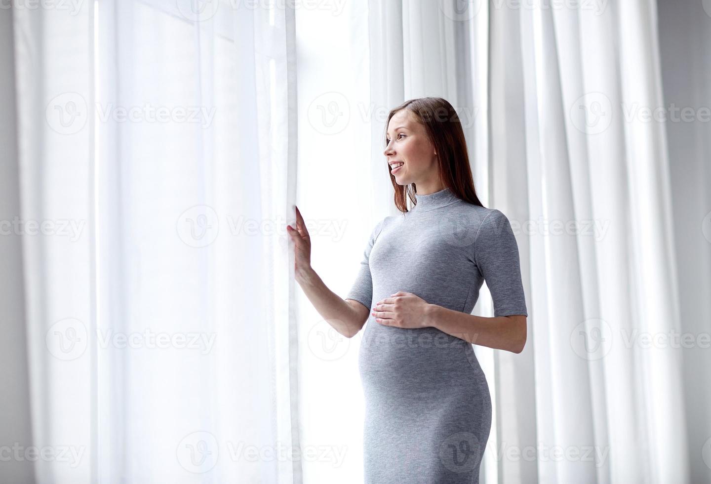 gelukkige zwangere vrouw met grote buik thuis foto