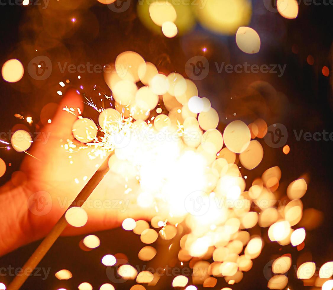 vonken en licht van sterretjes in het donker op de palm van een persoon. kerstmagie, oudejaarsavond, feestelijke achtergrond. ruimte voor tekst foto