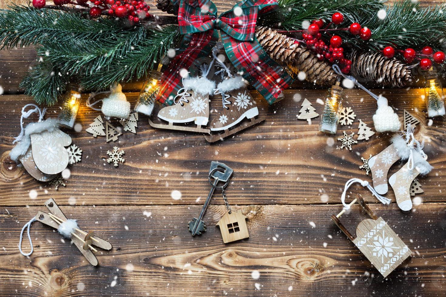 huissleutel met sleutelhanger huisje op een feestelijke milieuvriendelijke, natuurlijke achtergrond met kerstboom. gelukkig nieuwjaar-rode achtergrond, cadeau, wenskaart. aankoop, bouw, verhuizing, hypotheek foto