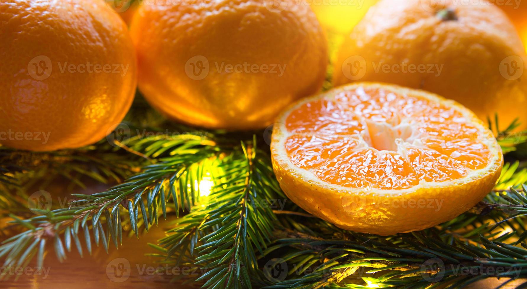 verse mandarijnen in slingerlichten, op dennentakken en klatergoud - de heldere achtergrond van het nieuwe jaar. de helft van een sinaasappel, citrusaroma van de vakantie. kerstmis, nieuwjaar. ruimte voor tekst. foto