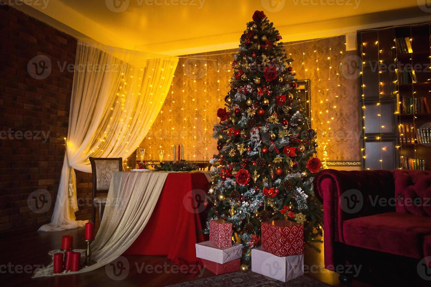 kerstinterieur van de donkere woonkamer van het huis. kerstboom, lampjes van slingers aan de muren, bibliotheekkast, boeken op de planken. luxe interieur. nieuwjaar, rode en gouden ballen. foto