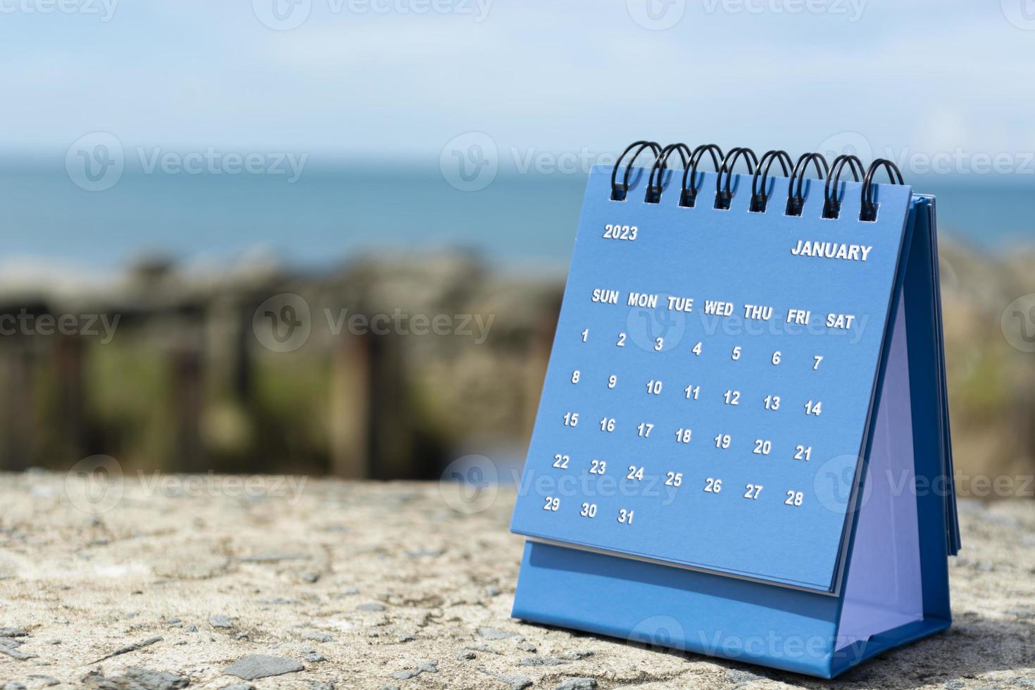 blauwe januari 2023 kalender op onscherpe achtergrond van blauwe oceaan. foto