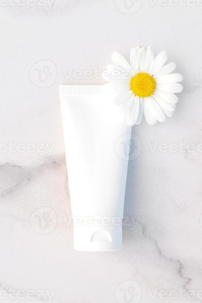 natuurlijke biologische cosmetische verpakkingen bespotten met bloemen van kamille. handcrème of lotion voor het verzachten van de huid. foto