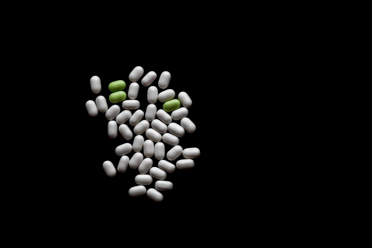witte en groene pillen op zwarte houten achtergrond met kopie ruimte foto