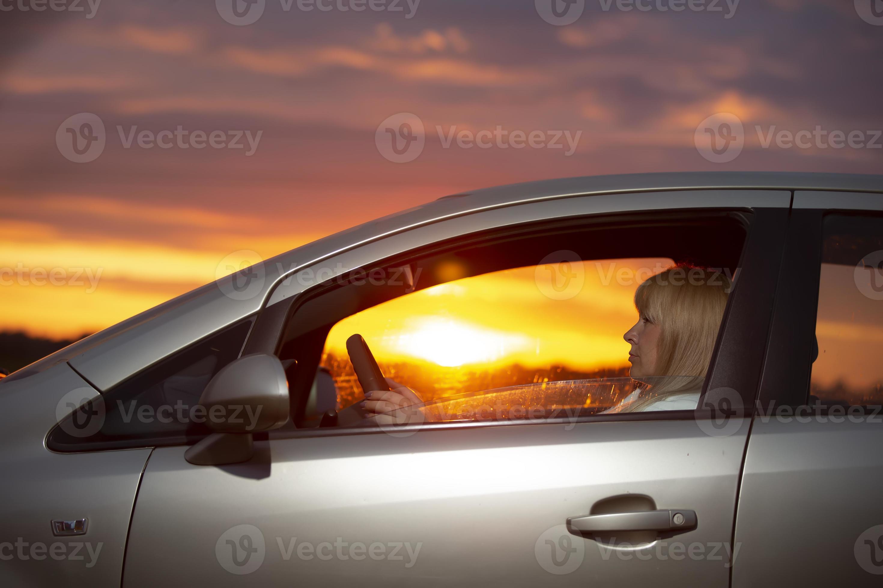 een middelbare leeftijd vrouw het rijden een tegen de backdrop van een zonsondergang Stockfoto