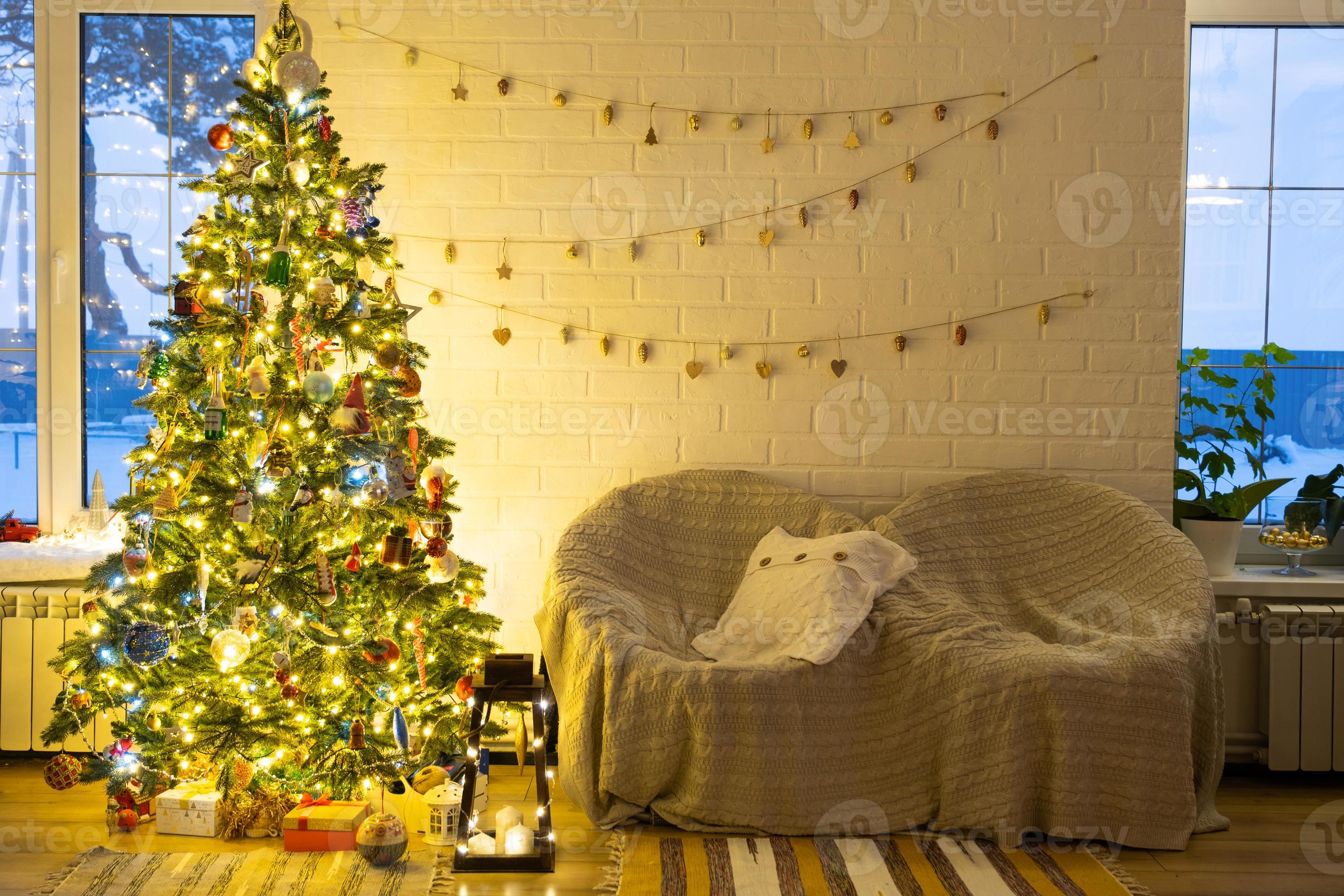 Kerstmis boom in wit interieur van een huis met loft-stijl steen muren met slingers van glas Aan een touw. gloeiend fee lichten decoratie van de studio kamer. knus huis in Kerstmis en nieuw jaar 17107892 stockfoto bij