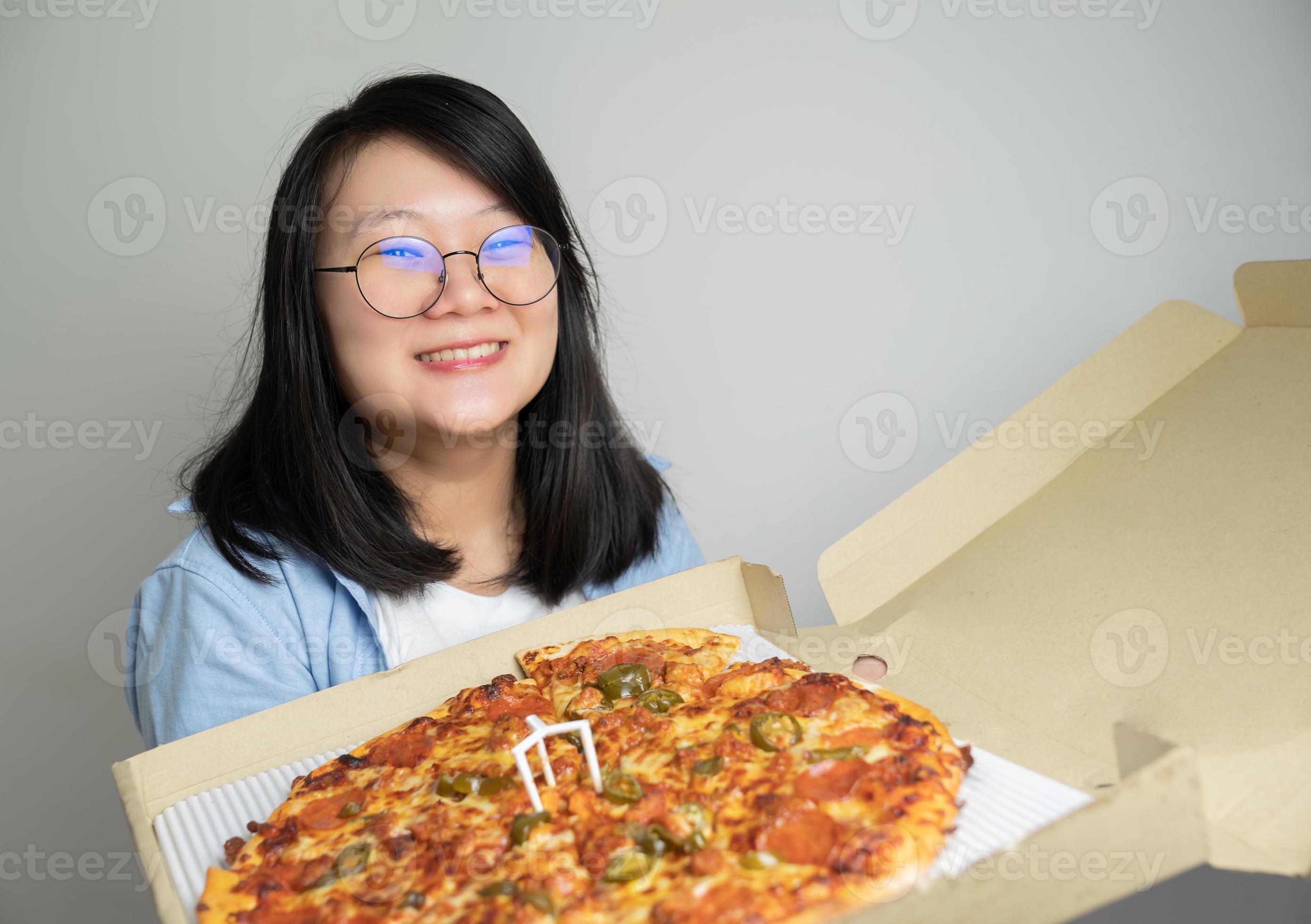 geweer Honger Shuraba aziatische bril jonge vrouw opent pizzadoos en windt zich op over de grote  pizza erin. fotograferen in studiolicht. 17150714 Stockfoto