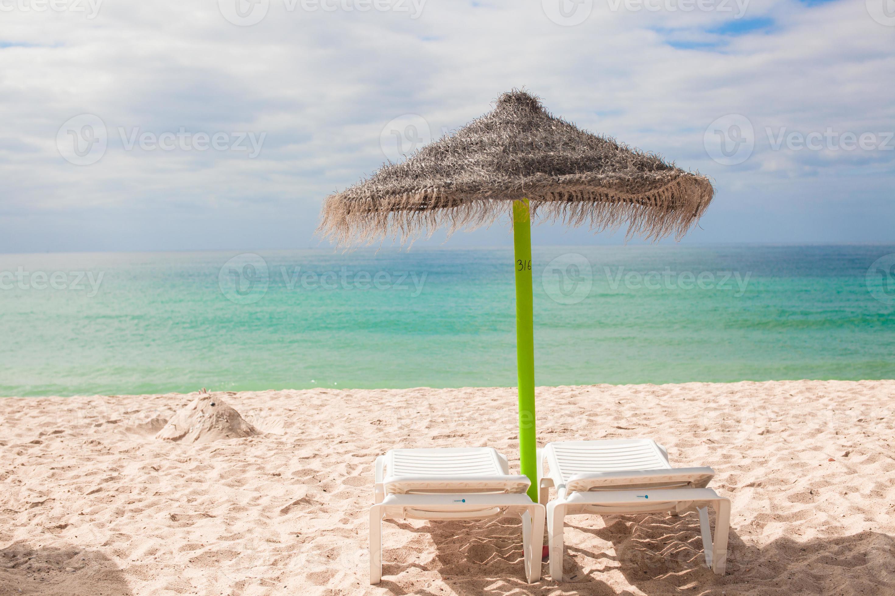 Aanbevolen spreken Articulatie strand ligstoelen en paraplu's Aan de exotisch toevlucht Bij woestijn kust  18055608 Stockfoto