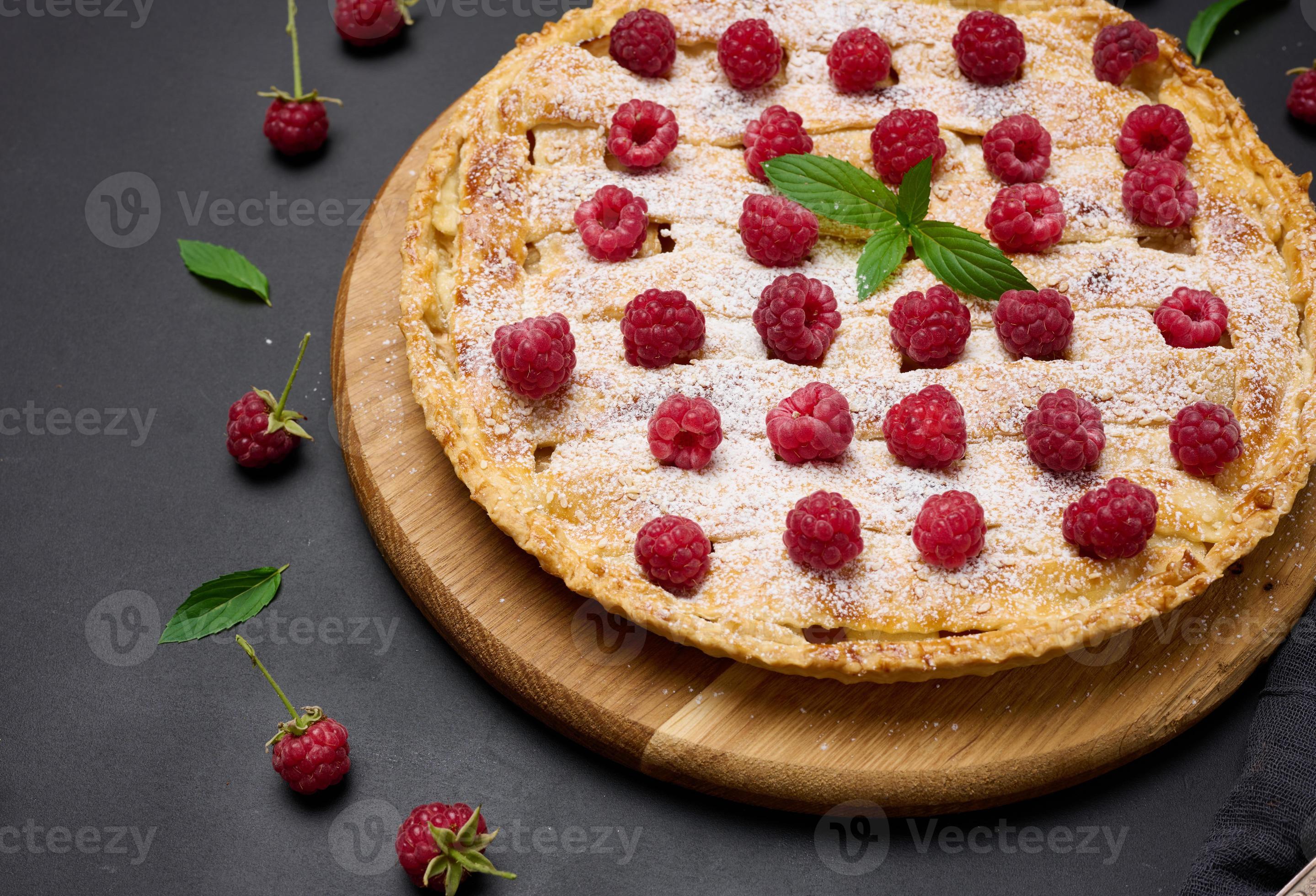 Spuug uit Onderverdelen heerlijkheid ronde gebakken taart met appels en besprenkeld met gepoederd suiker Aan een  zwart tafel. 18959100 Stockfoto