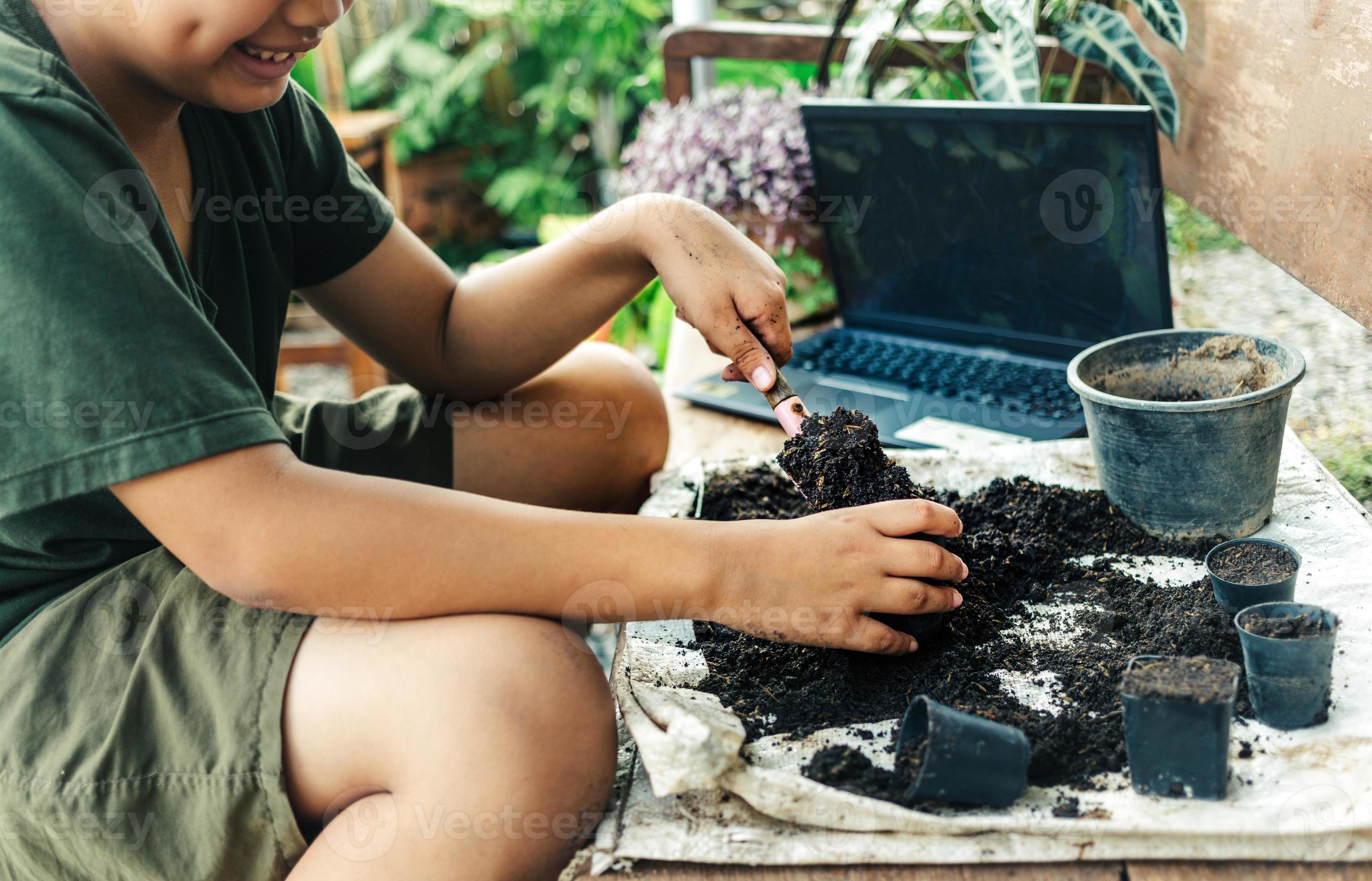 jongen toenemen bloemen in potten door online onderwijs. scheppen bodem in potten naar bereiden planten voor aanplant vrije tijd activiteiten concept 19568380 stockfoto bij Vecteezy