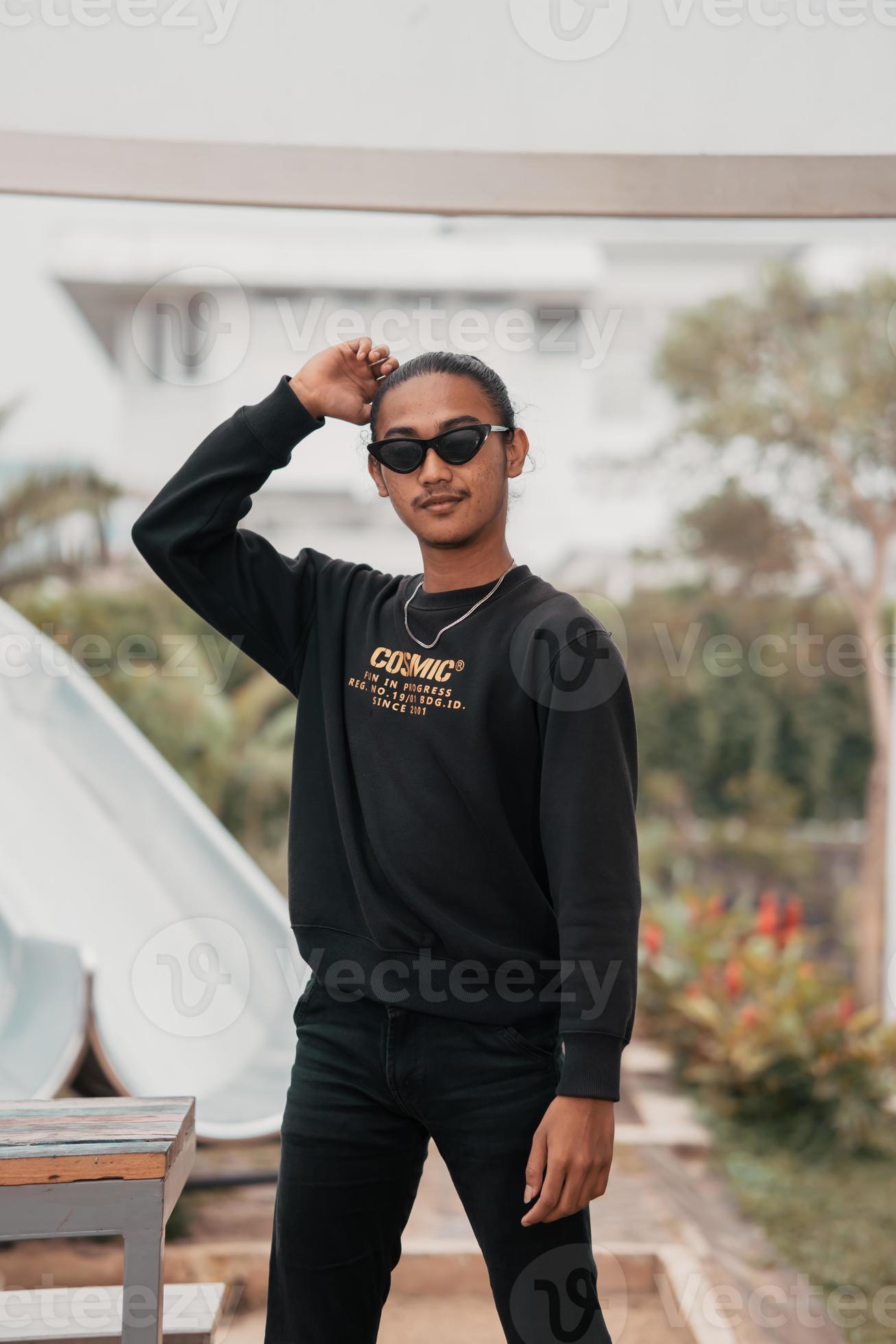 Vaardigheid olie Onmogelijk een Aziatisch tiener in een overhemd en zonnebril staat heel mannelijk  terwijl poseren in een park 20444025 Stockfoto