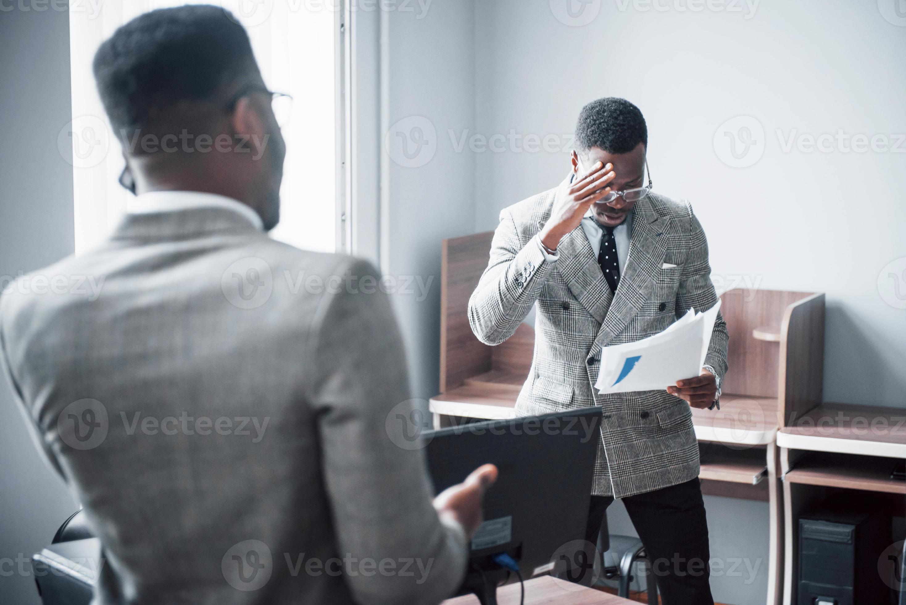 moderne zakenman op het werk. twee zelfverzekerde zakenmensen in formele kleding die iets bespreken terwijl een van hen naar de documenten kijkt en de tweede een belangrijk telefoontje foto