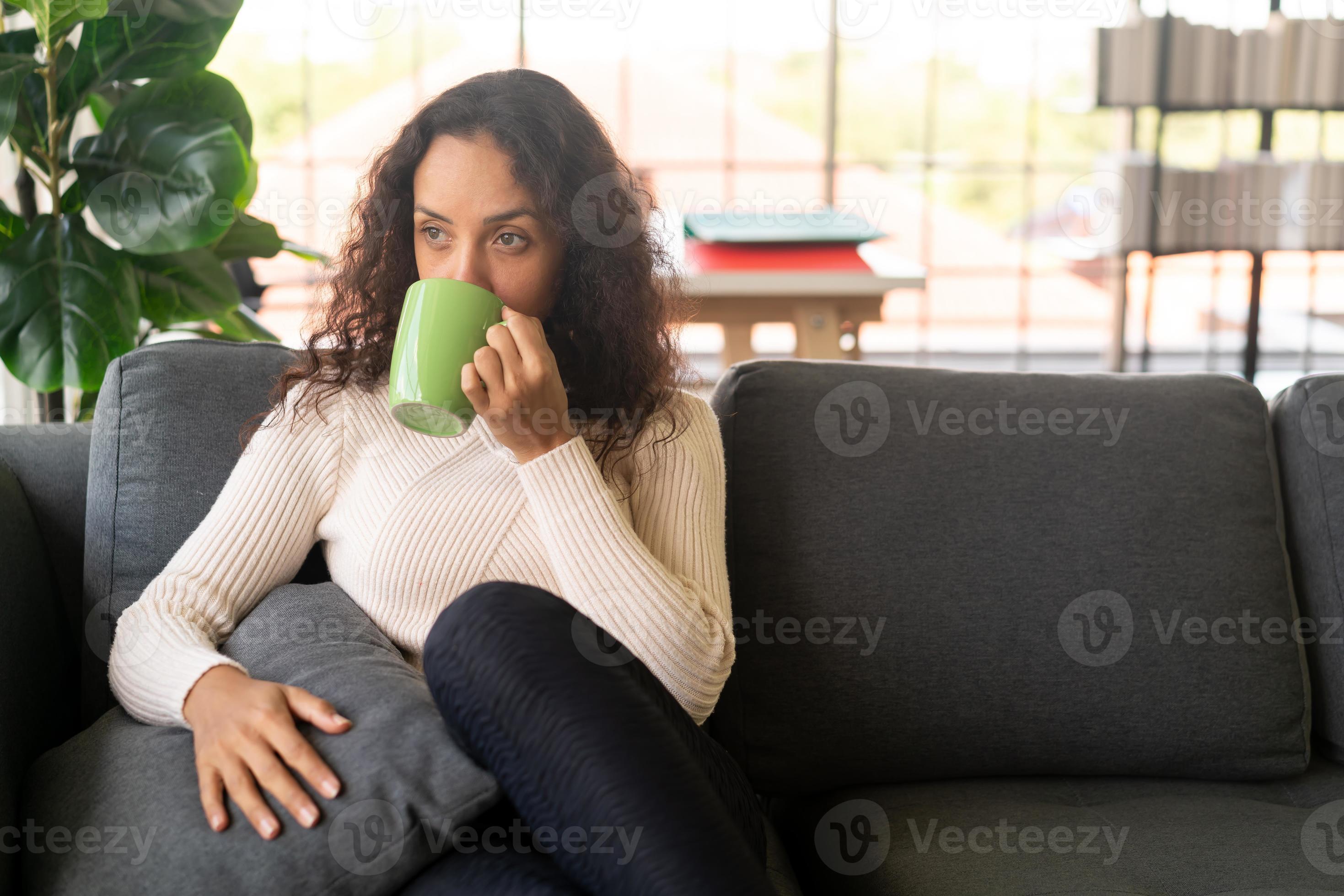 Latijnse vrouw die koffie drinkt op de bank foto