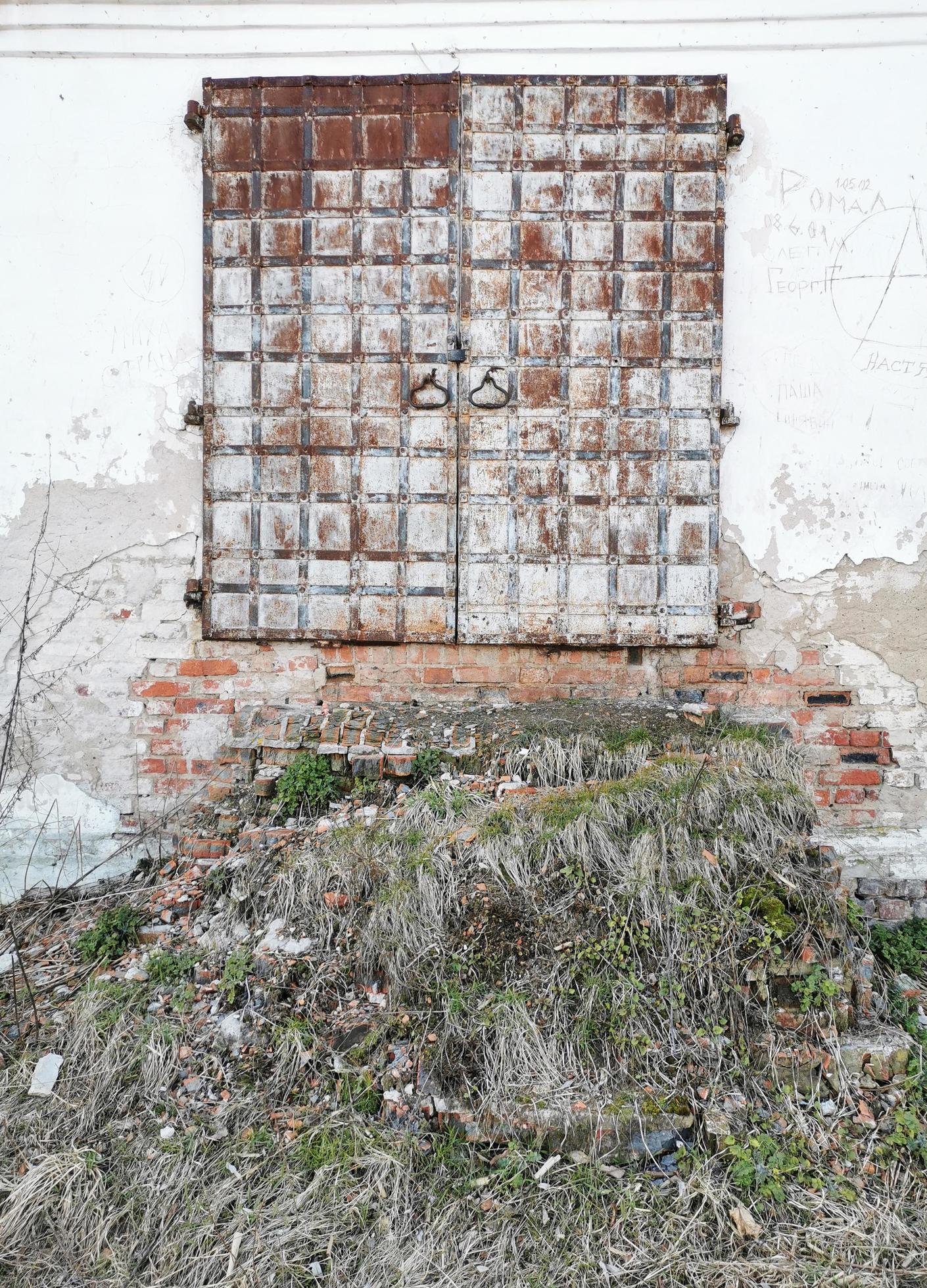 huilen generatie Mordrin oude deuren van het klooster met een vervallen trap. de gammele muren waren  begroeid met gras. metalen deur. 5171095 Stockfoto