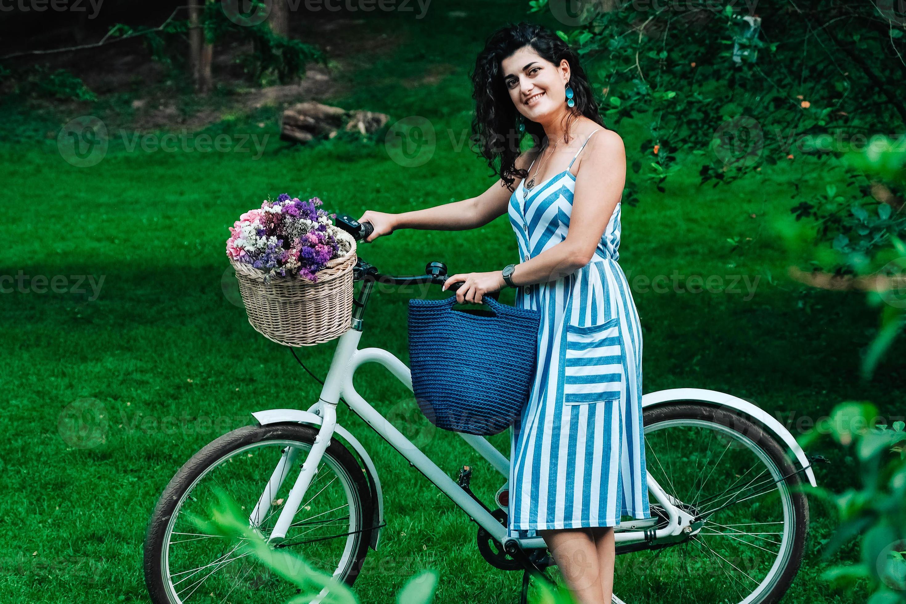 Verwaand Zonsverduistering orkest vrouw gekleed in een gestreepte jurk staat naast een fiets met een mand met  bloemen in park 5272771 Stockfoto