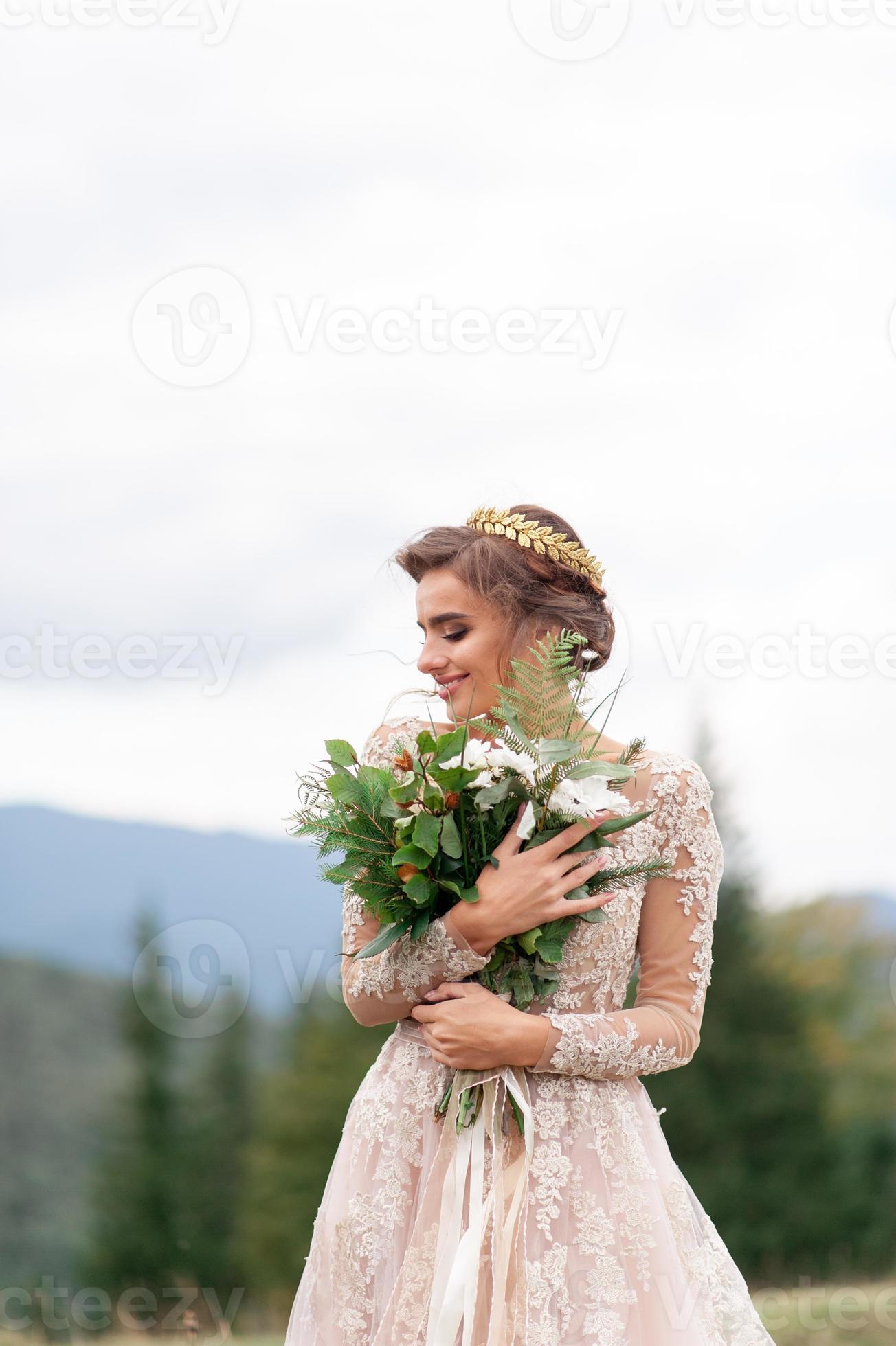 Medic Absorberend Gladys mooie bruid poseren in haar trouwjurk op een achtergrond van bergen. in  haar handen houdt ze een boeket wilde bloemen. 5340789 Stockfoto