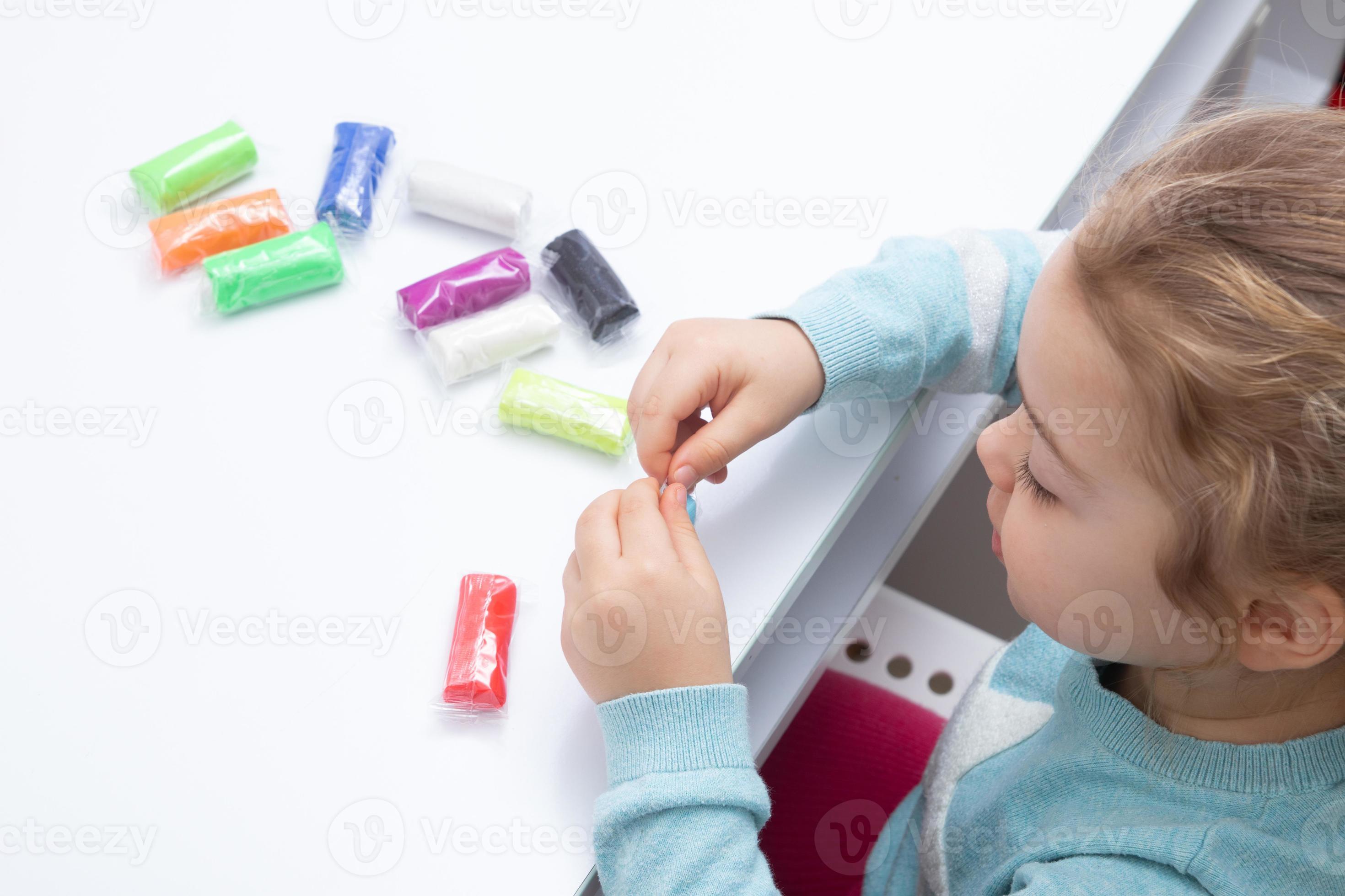 Prominent Durven smeren het meisje aan tafel speelt met boetseerdeeg. kinderspelletjes voor fijne  motoriek 5411499 Stockfoto