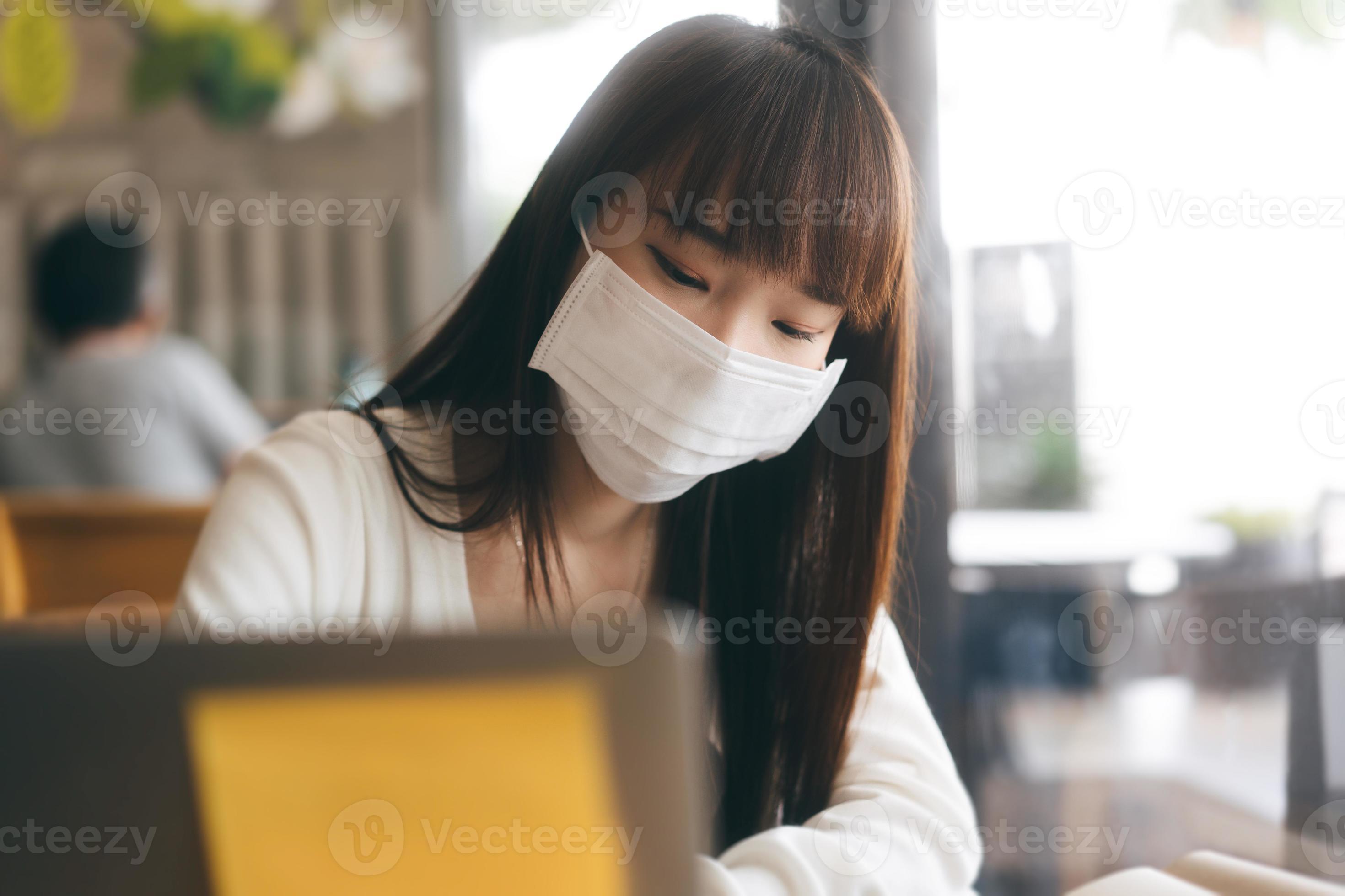 jonge volwassen aziatische vrouw met beschermend gezichtsmasker voor virus covid 19 werk en studie in café op dag. foto