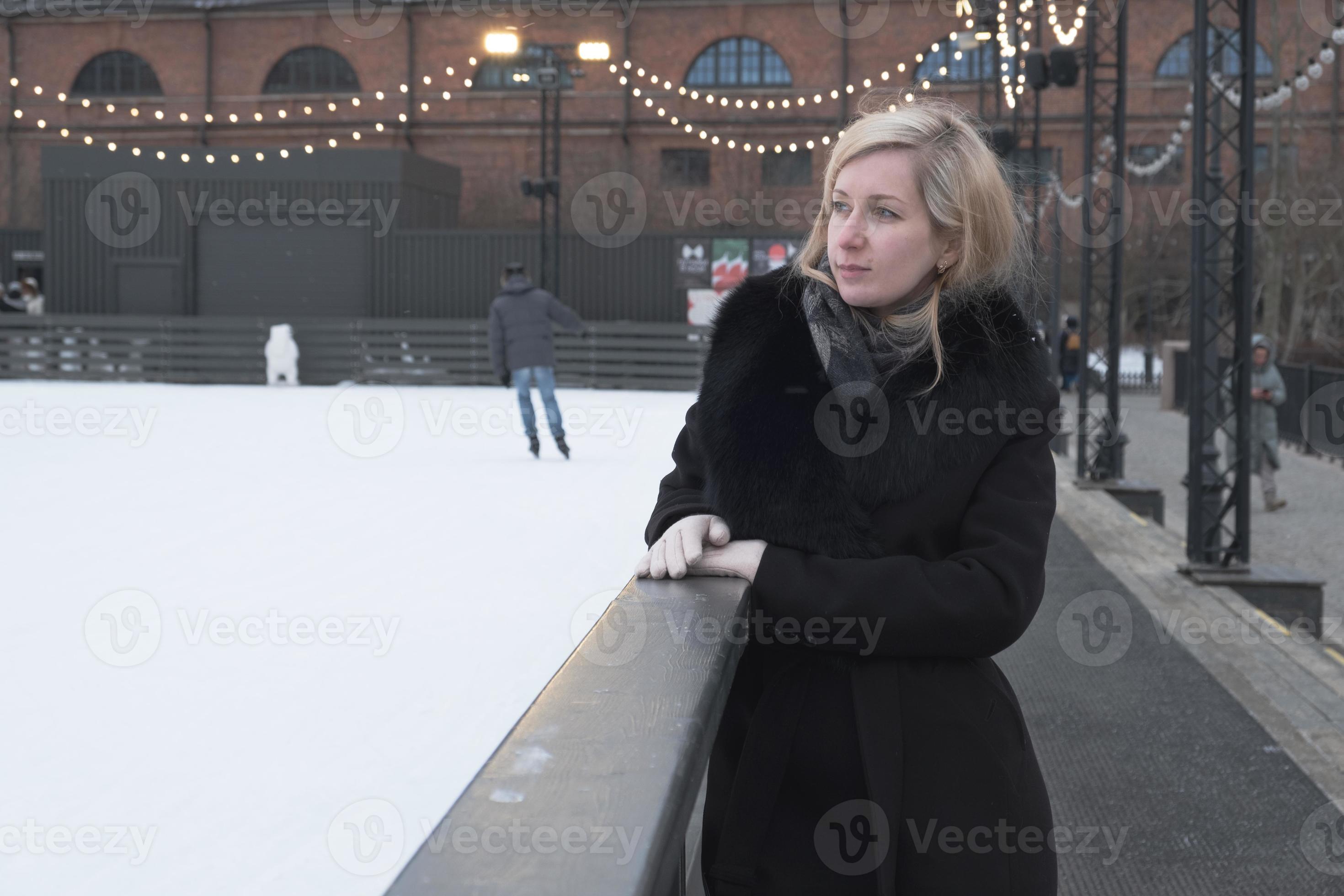 kwaad Subtropisch converteerbaar blonde vrouw in jas met bontkraag staat aan de zijkant van de ijsbaan.  7473152 Stockfoto