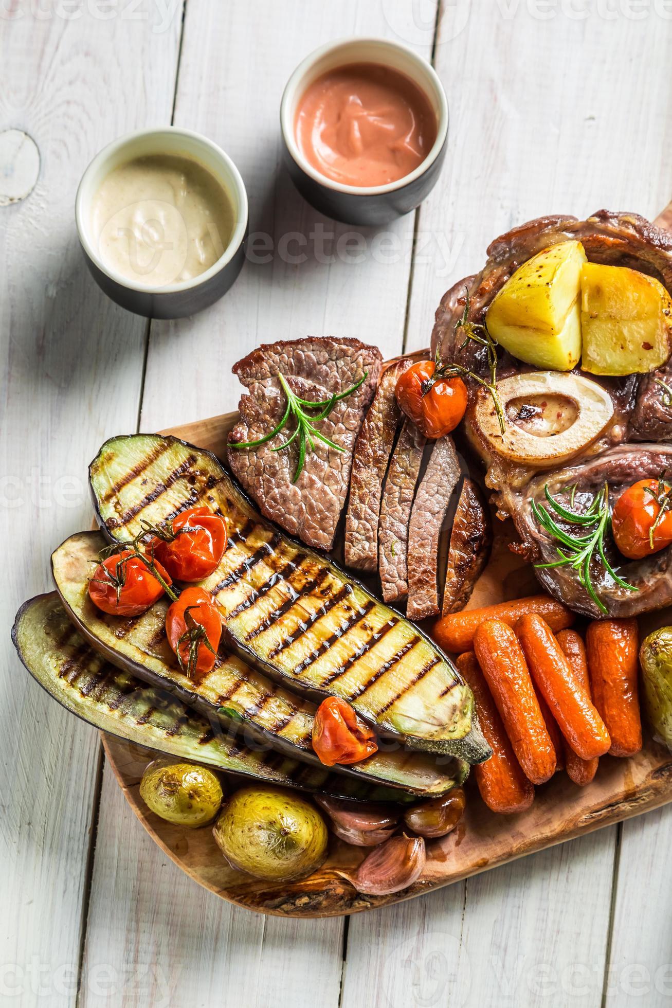 geroosterde biefstuk en groenten met kruiden op een houten bord foto