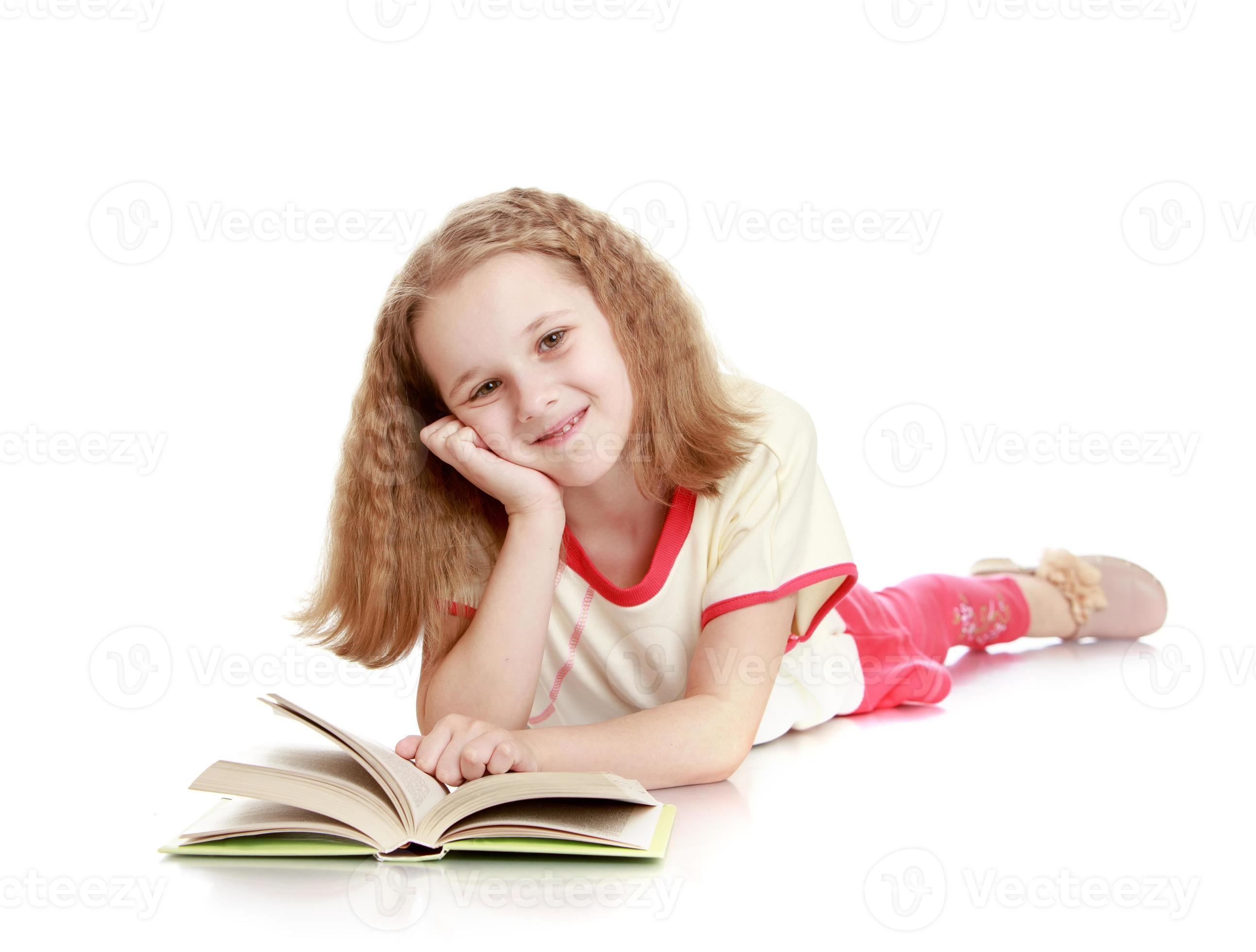 het meisje ligt op de grond en leest een boek foto