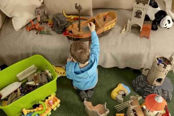 weinig Kaukasisch jongen met blauw capuchon spelen met kleurrijk speelgoed Bij huis. kind hebben plezier. gelukkig en vrolijk kind Toneelstukken met schip, dinosaurussen, kasteel. tijd werkzaamheid, huiselijk leven. knus kamer. 15591088