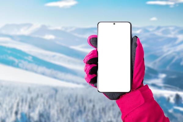 bunker landinwaarts Redenaar gebruik makend van een mobiel telefoon Bij de ski toevlucht. geïsoleerd  Scherm voor bevorderen ski of bergbeklimmen app. telefoon in hand- met roze  handschoen. ski toevlucht in achtergrond 17663892 Stockfoto