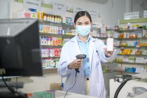 portret van vrouwelijke apotheker die gezichtsmasker draagt in een moderne apotheekdrogisterij. foto