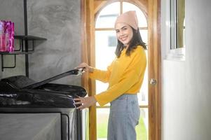 jonge gelukkige vrouw die de was doet met een wasmachine thuis, wasconcept foto