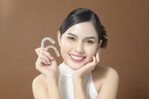 een jonge vrouw met mooie tanden houdt invisalign, gezond tandconcept foto