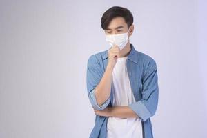 jonge aziatische man met beschermend masker over witte achtergrond studio, veiligheidsreizen, nieuw normaal, sociale afstand, covid19 en pandemisch concept.