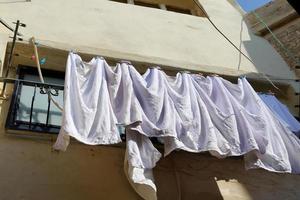 gewassen linnen droogt op straat buiten het raam van het huis. foto