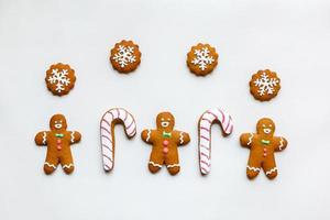 handgemaakte feestelijke peperkoekkoekjes in de vorm van sterren, sneeuwvlokken, mensen, sokken, personeel, wanten, kerstbomen, harten voor kerstmis en nieuwjaarsvakantie op witboekachtergrond foto