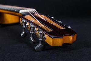 stemsleutels op houten machinekop van zes snaren akoestische gitaarhals op zwarte achtergrond foto