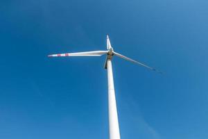 roterende bladen van een windmolenpropeller op blauwe hemelachtergrond. opwekking van windenergie. pure groene energie. foto