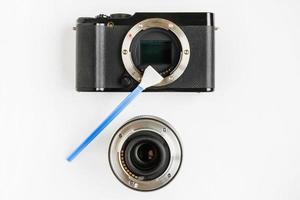 close-up van spiegelloze digitale aps-c vuile camera matrix sensor reiniging en onderhoud met wattenstaafje, fotograaf reiniging fotocamera op witte achtergrond foto