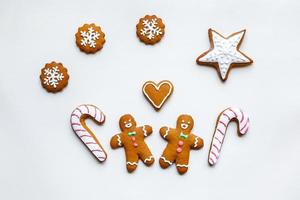 handgemaakte feestelijke peperkoekkoekjes in de vorm van sterren, sneeuwvlokken, mensen, sokken, personeel, wanten, kerstbomen, harten voor kerstmis en nieuwjaarsvakantie op witboekachtergrond foto