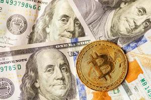 virtueel geld gouden bitcoin op honderd dollar rekeningen achtergrond. wissel bitcoin contant in voor een dollar. foto