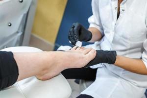 de meester in zwarte handschoenen in de salon maakt manicure-pedicure aan de klant foto