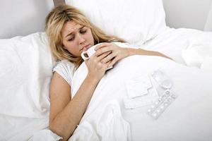 vrouw die lijdt aan koude met koffie in bed foto