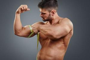 bodybuilder die biceps met meetlint meet