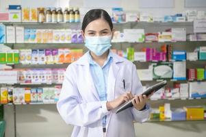 portret van vrouwelijke apotheker die gezichtsmasker draagt in een moderne apotheekdrogisterij. foto