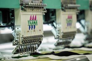 moderne en automatische hoogtechnologische naaimachine voor het productieproces van textiel of kleding voor het maken van kleding in de industrie. digitale textielindustrie. computergestuurd borduren. foto