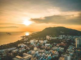 vung tau luchtfoto van de stad met prachtige zonsondergang en zoveel boten. panoramisch uitzicht op de kust van vung tau van bovenaf, met golven, kustlijn, straten, kokospalmen en tao phung-berg in vietnam. foto